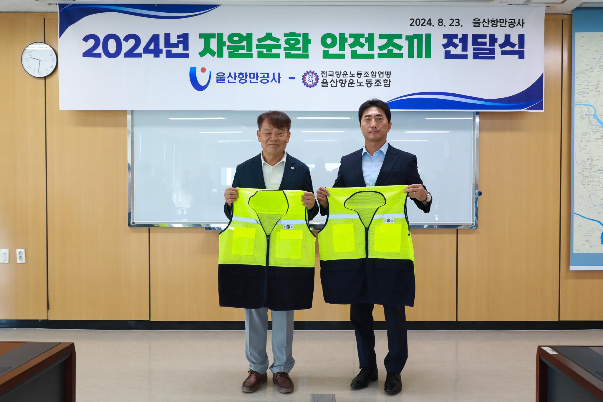 UPA 김재균 사장(왼쪽)이 울산항운노동조합 김석호 위원장에게 안전조끼 전달식을 갖고 기념사진을 찍고 있다